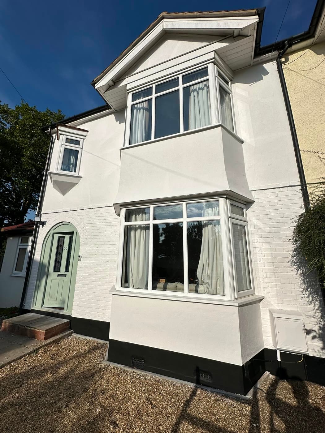 Decorator painting exterior render and sash windows on a Victorian SW London terrace
